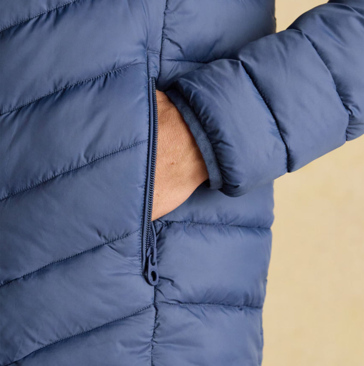 Joules Garrett Blue Showerproof Padded Jacket detail view of zipped pocket on sleeve in blue nylon material.