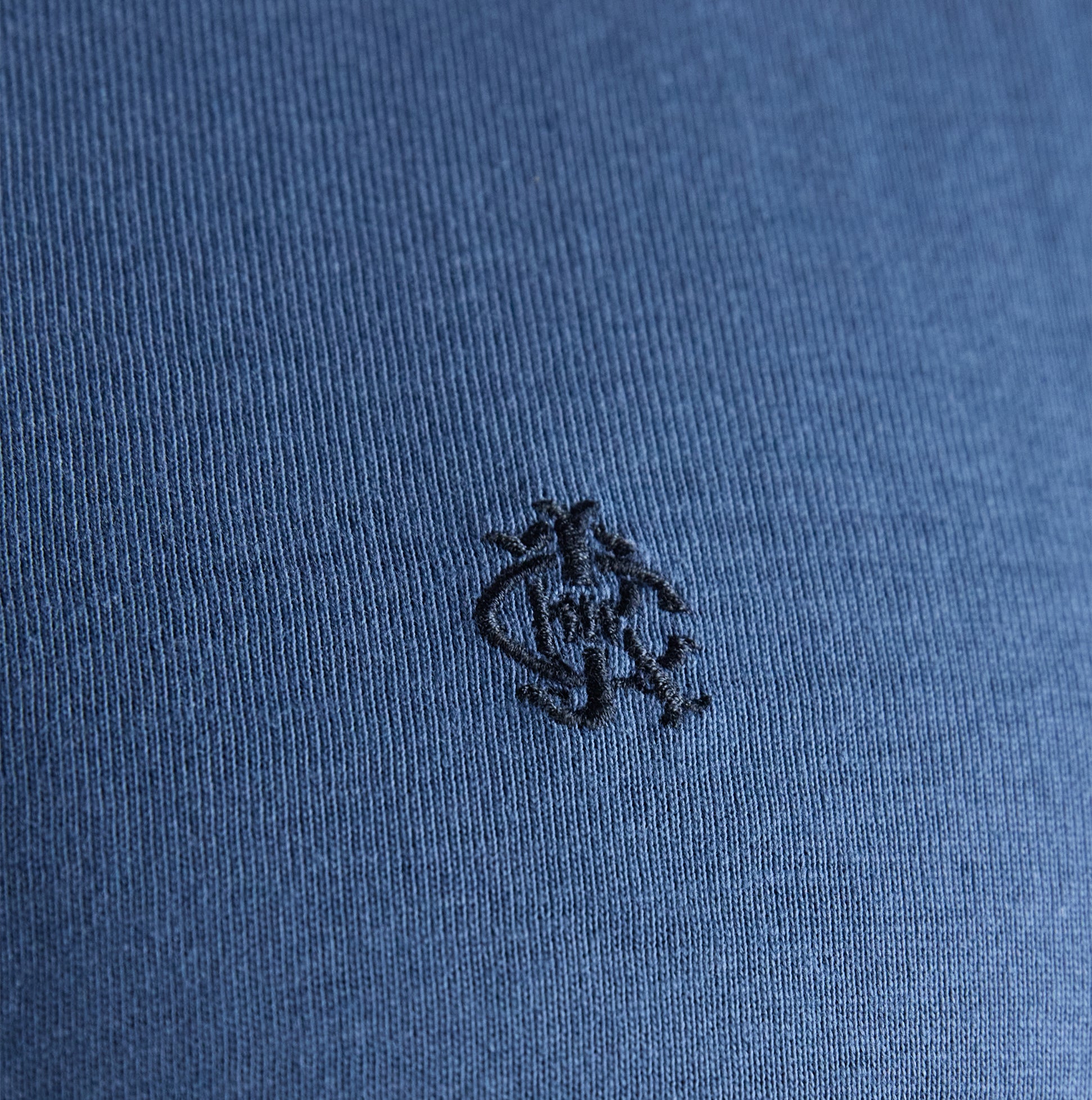 Joules RUGBY CLUB TEE Mens T-Shirt Blue detail view of fabric texture and logo embroidery on blue shirt.