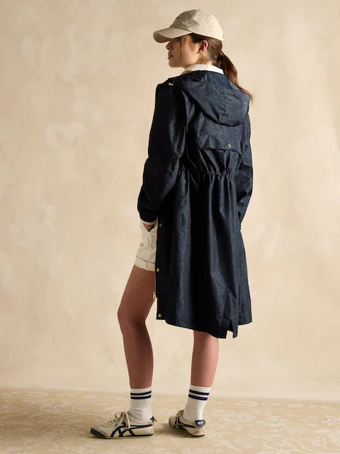 Joules HOLKHAM Womens Raincoat Navy Paisley side view, featuring hood and adjustable waist, worn with cap and sneakers.