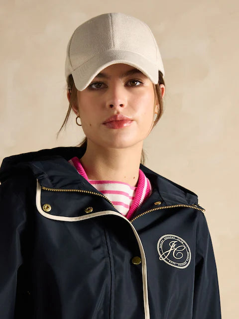 Joules Holt Waterproof Packable Raincoat with Hood Navy front view on model wearing beige cap.