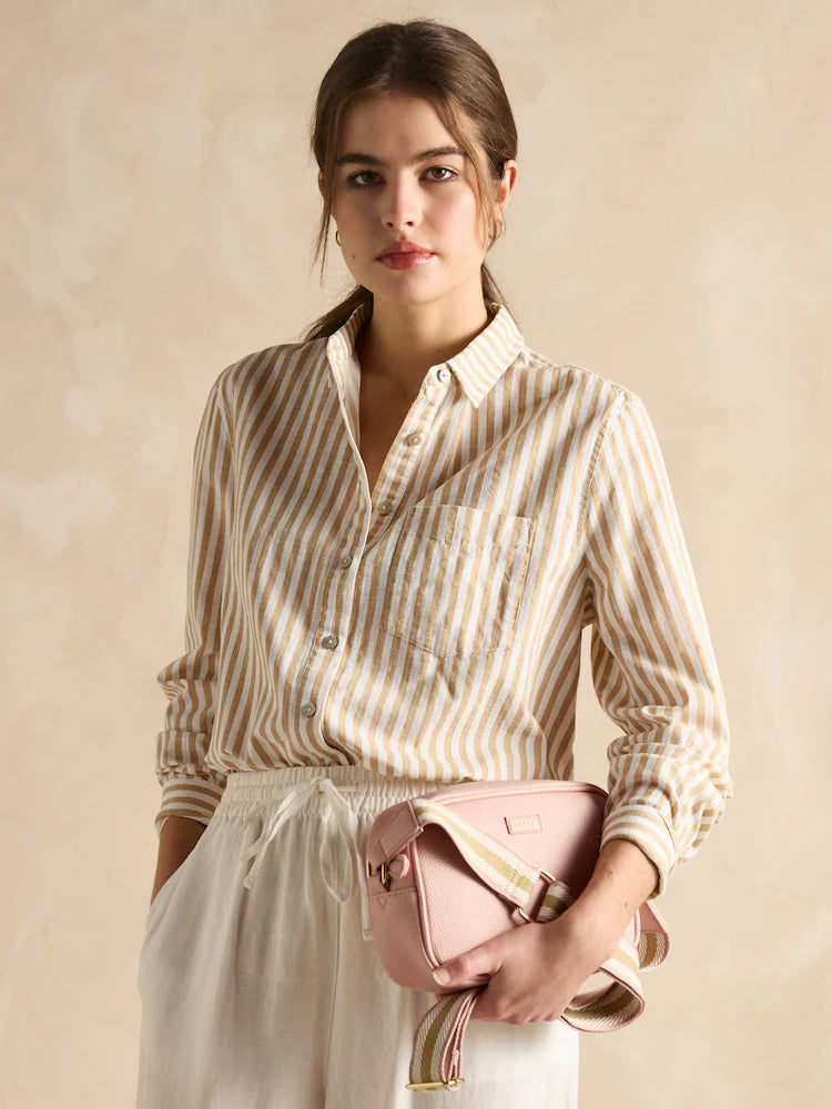 Joules TRENT Womens Cross Body Bag Pale Pink held by a model wearing a striped shirt, front view with a soft background.