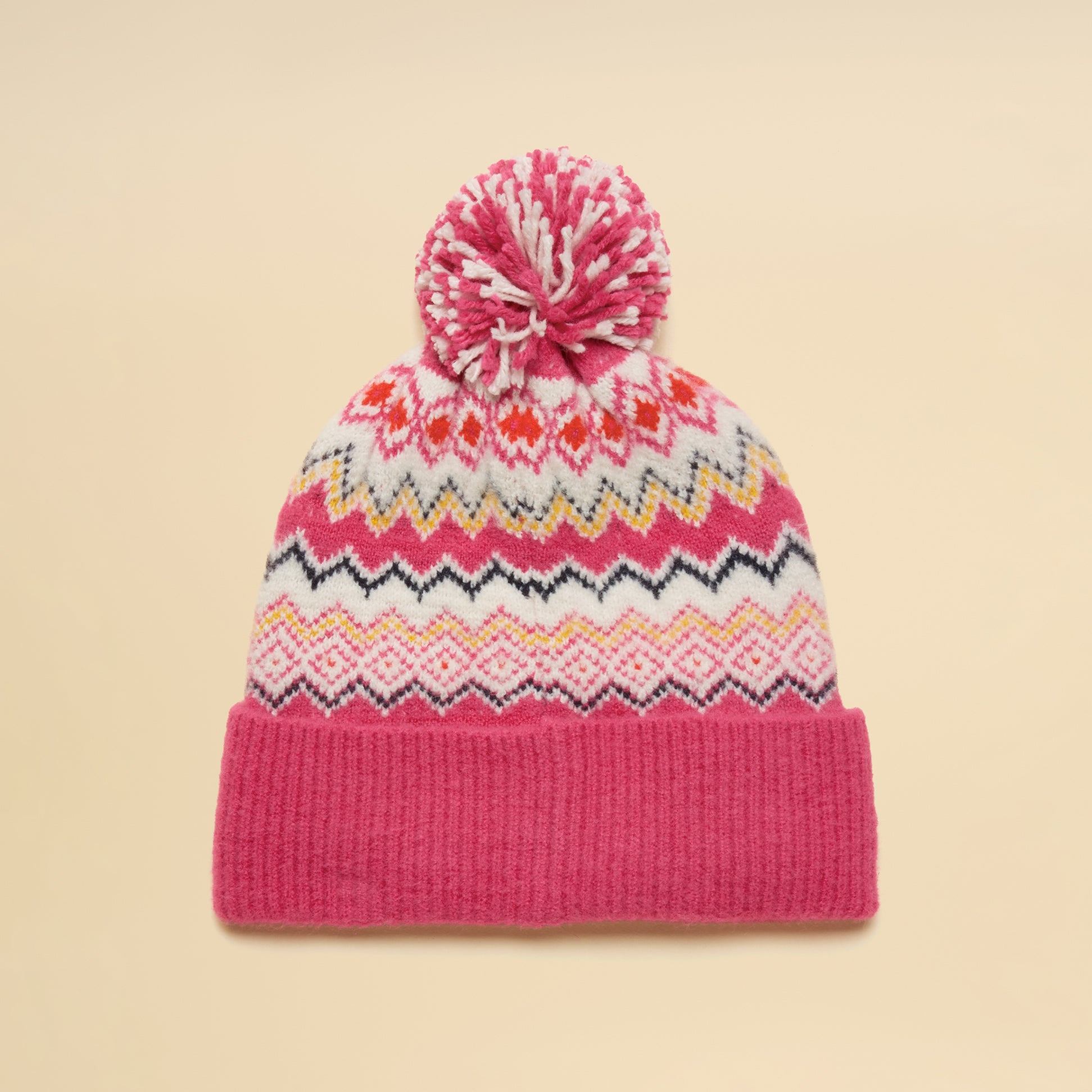 Joules KARA BOBBLE Womens Beanie Hat Pink top view with pom pom and colorful ethnic patterns on a beige background.