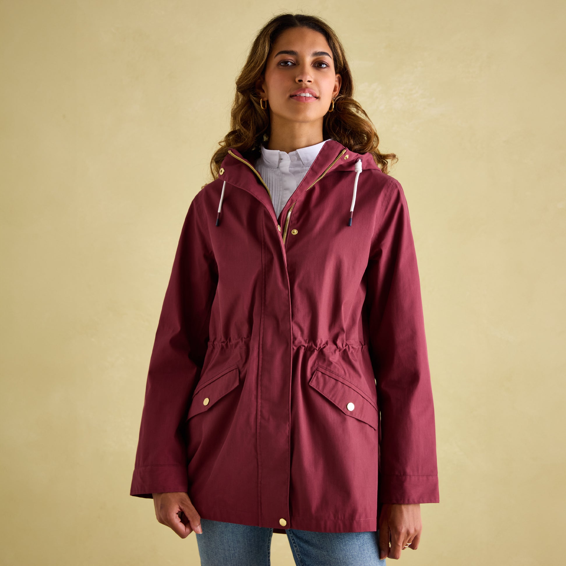 Joules PORTWELL Womens Raincoat Port front view, featuring adjustable hood and waist in burgundy color.