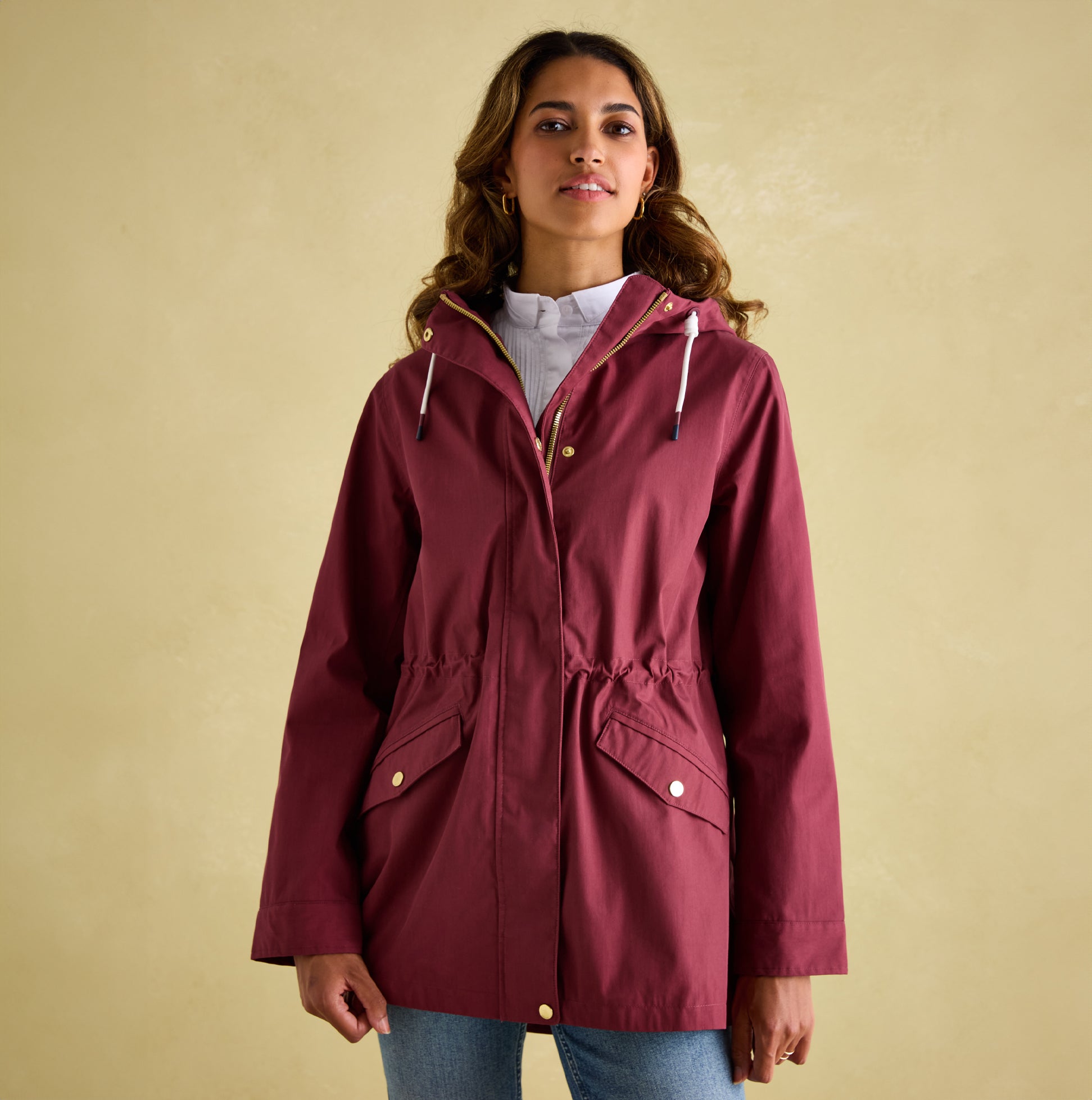 Joules PORTWELL Womens Raincoat Port front view, featuring adjustable hood and waist in burgundy color.