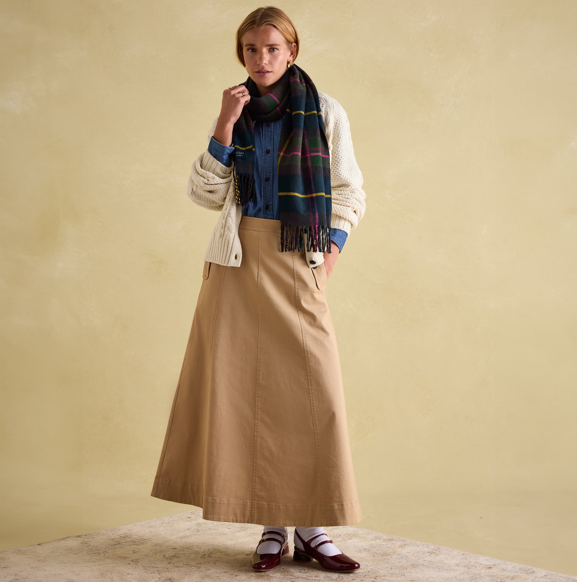 Joules LANGTREE Womens Scarf Navy Check worn by a model, styled with a cream cardigan and beige skirt, front view.
