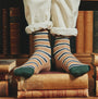 Joules KINGSBURY 2-Pack Mens Socks Navy Camel knee-level view showing striped design on feet with books in background.