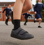 Kickers 117412 KODY TWIN Unisex School Shoes Black side view on child's foot during playtime in schoolyard.