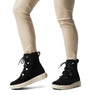 Sorel EXPLORER III JOAN Womens Winter Boots Black side view on model wearing fitted pants.