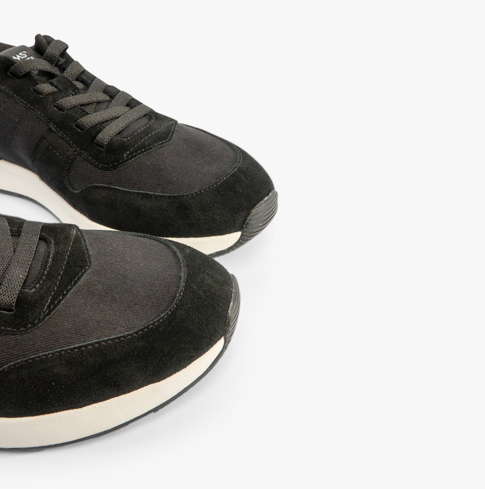 TOMS TRVL LITE RETRO Mens Trainers Black close-up view showcasing suede upper and lace-up design.