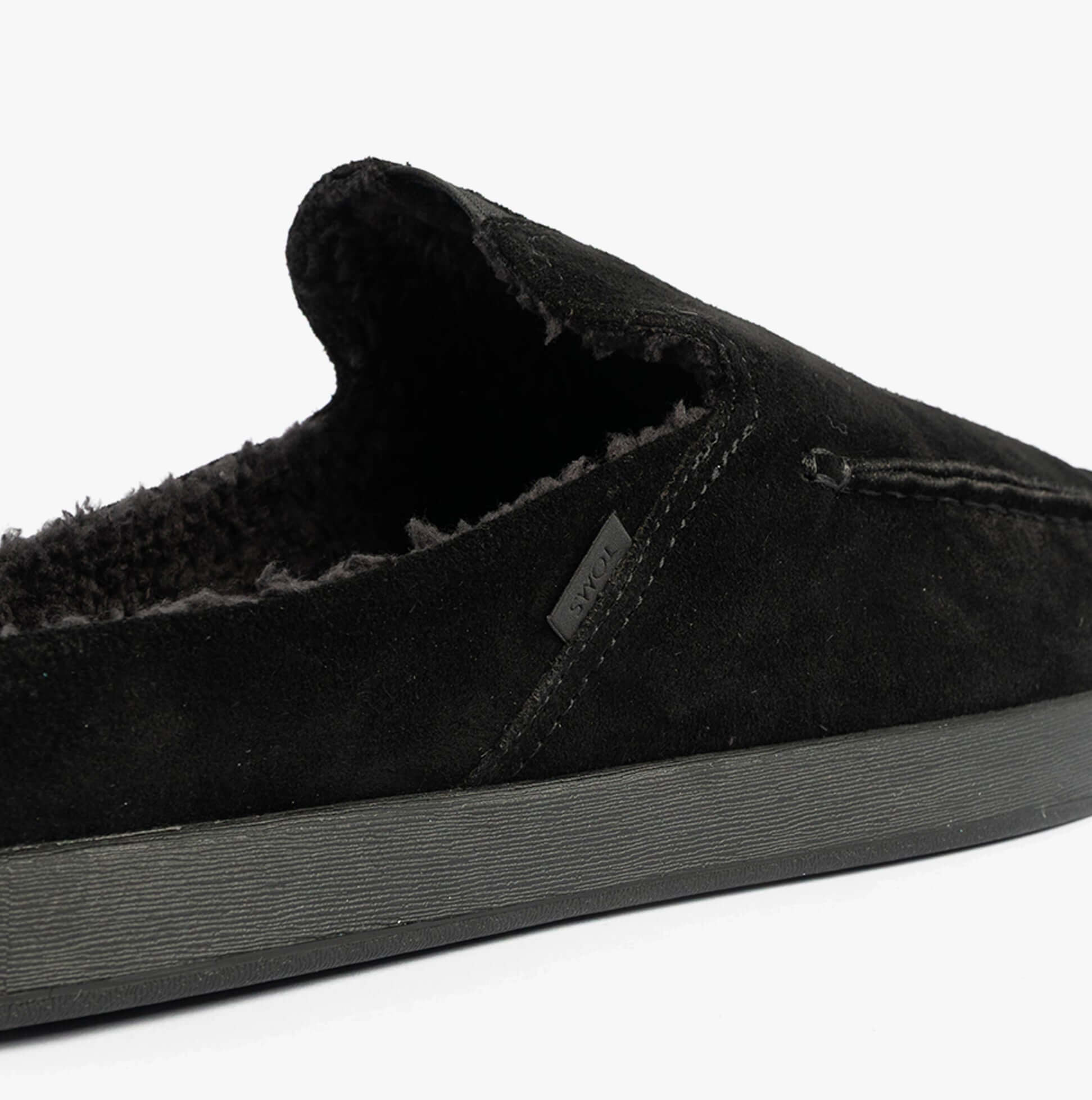 TOMS ALONSO MULE Mens Faux Shearling Lined Slippers Black side view showing suede upper and warm lining detail.
