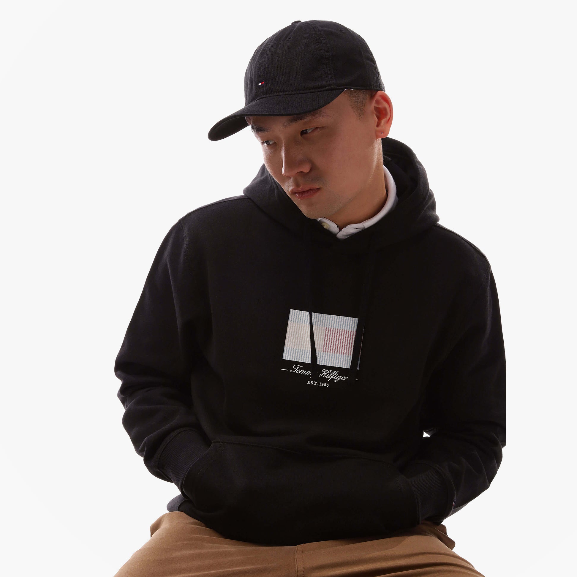 Tommy Hilfiger Flag Baseball Cap Black side view on model wearing hoodie, showcasing adjustable strap and cotton material.