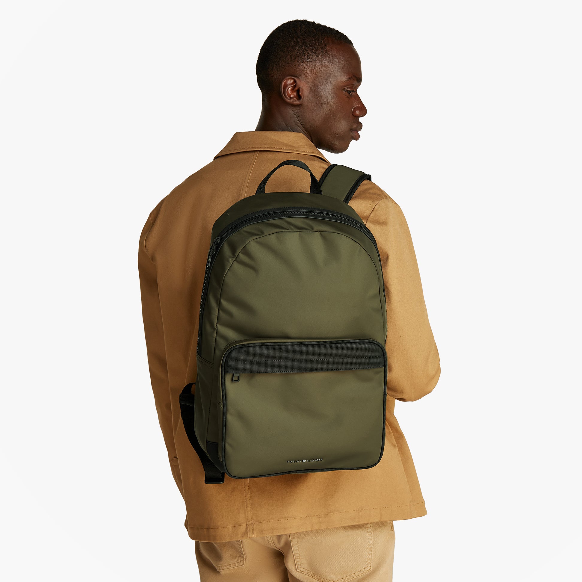 Tommy Hilfiger REPREVE Metal Logo Backpack Army Green, back view on model, showcasing adjustable padded shoulder straps.