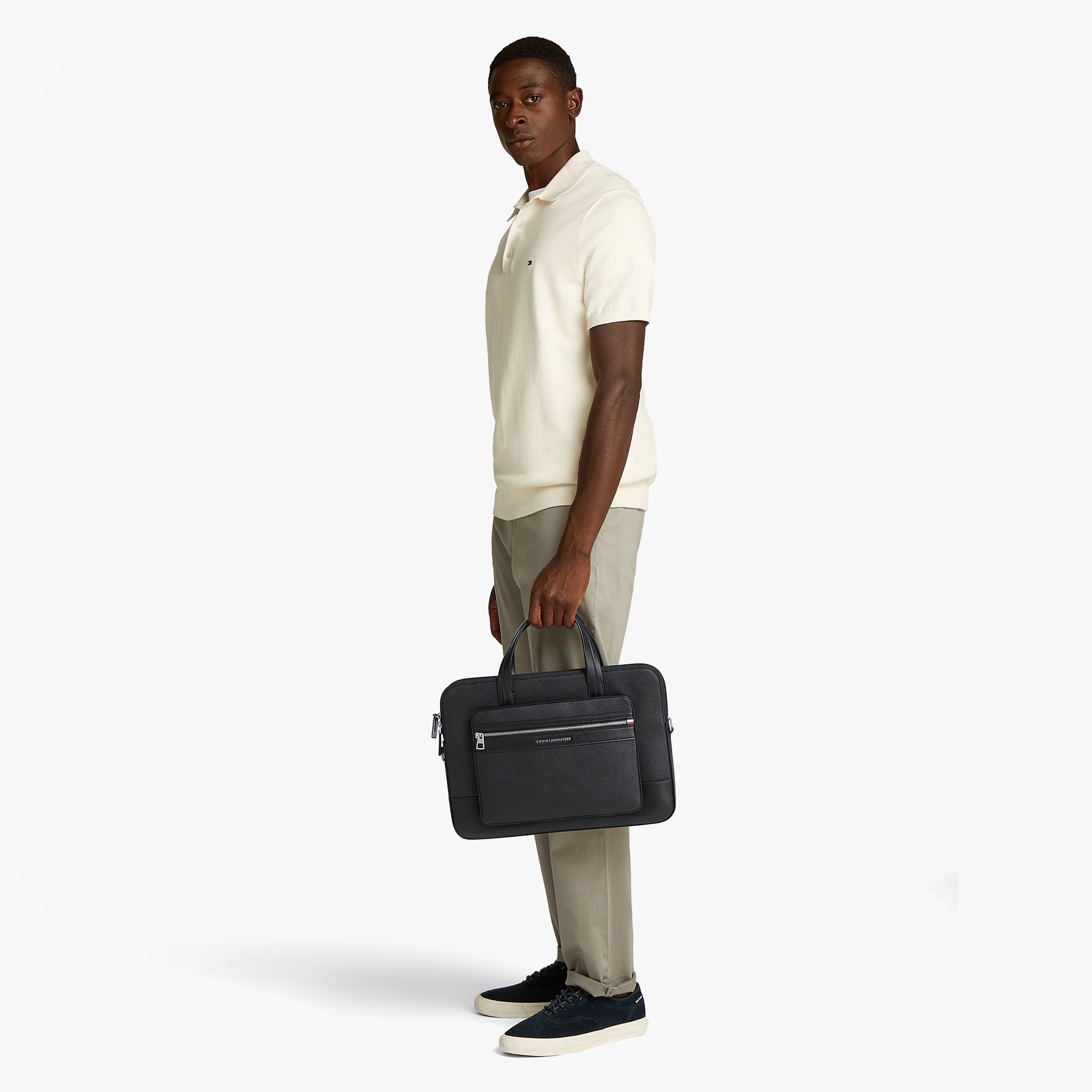 Tommy Hilfiger PEBBLE GRAIN METAL LOGO Mens Laptop Bag Black side view held by model in casual attire.