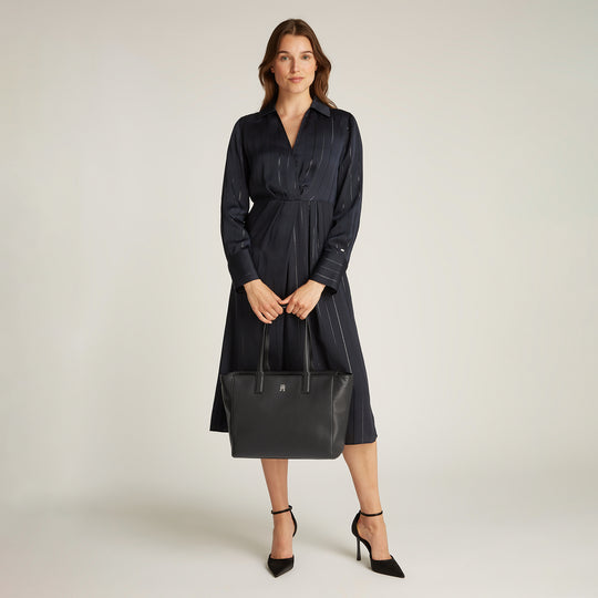 Tommy Hilfiger SOFT LOGO TOTE Womens Handbag Black held by model in a black dress, front view showcasing the handbag's zip closure and TH monogram.