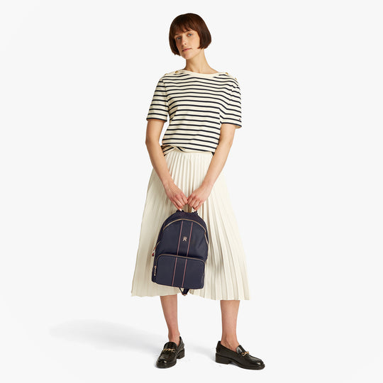 Tommy Hilfiger POPPY CORP Womens Backpack Space Blue Corp in front view with model wearing striped shirt and pleated skirt.