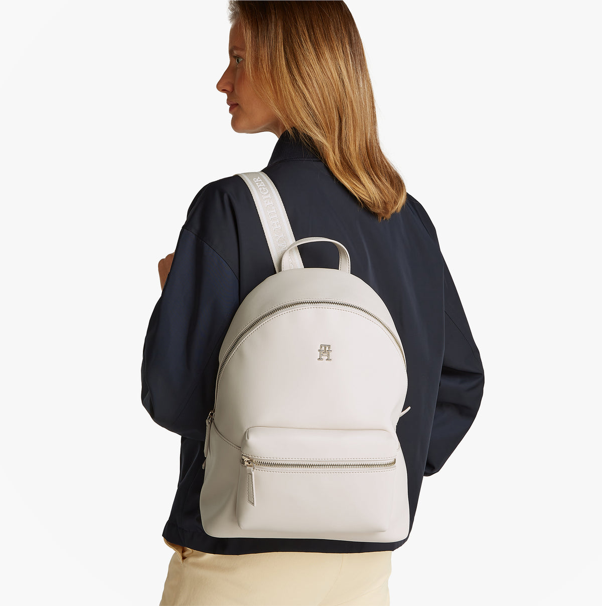 Tommy Hilfiger LOGOTAPE Womens Backpack Sugarcane side view on model with adjustable straps and TH monogram plaque.