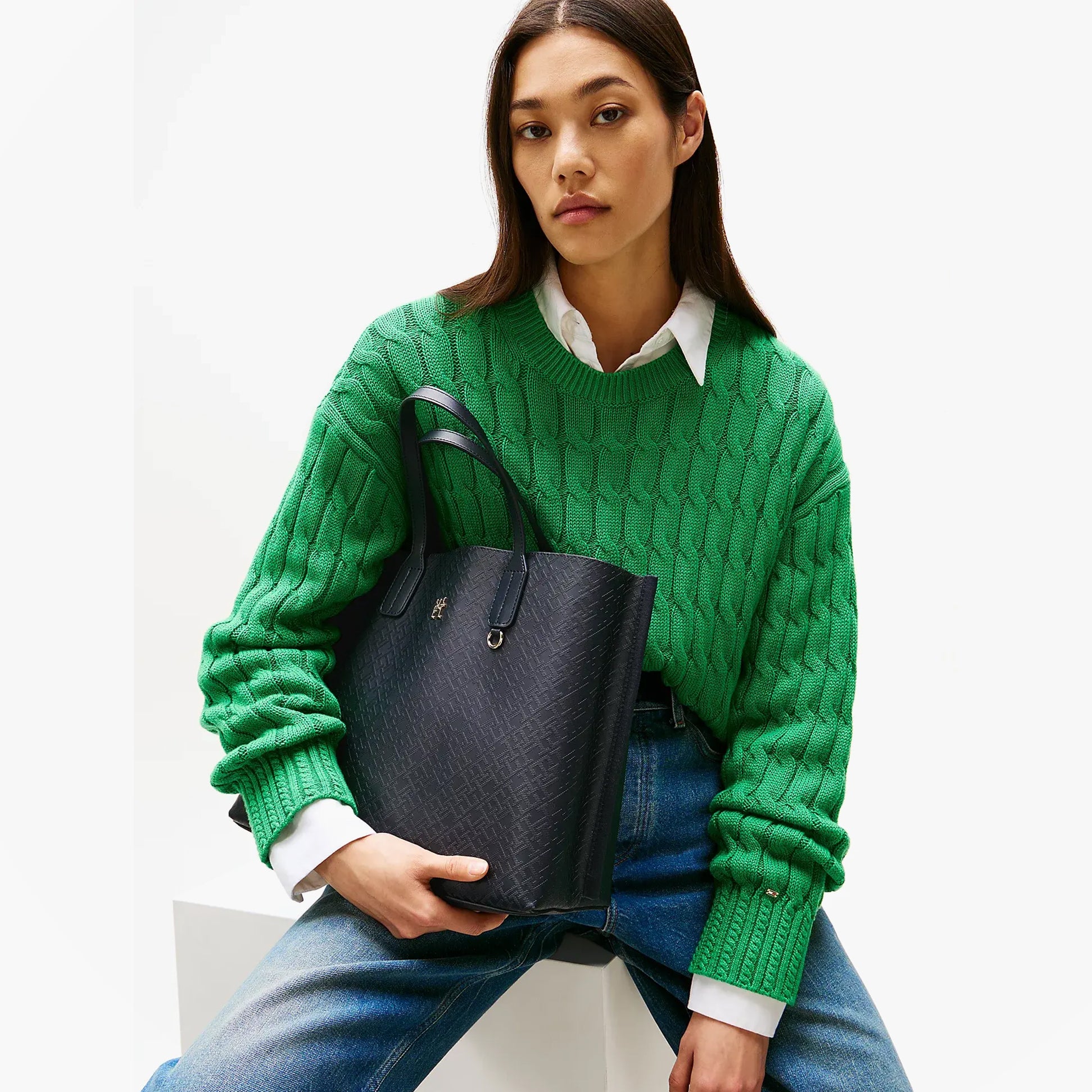 Tommy Hilfiger DISTINCT SATCHEL Ladies Handbag Space Blue held by model in green sweater, front view showcasing its elegant design.