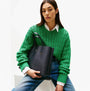 Tommy Hilfiger DISTINCT SATCHEL Ladies Handbag Space Blue held by model in green sweater, front view showcasing its elegant design.