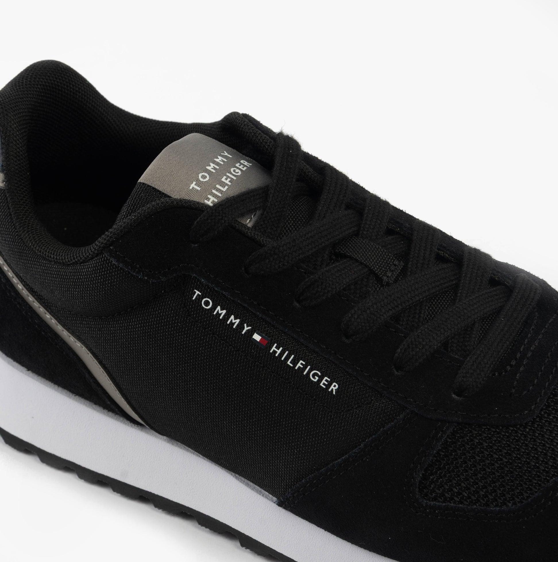 Tommy Hilfiger SUEDE LOGO Mens Trainers Black close-up view showing laces and logo details on black suede.