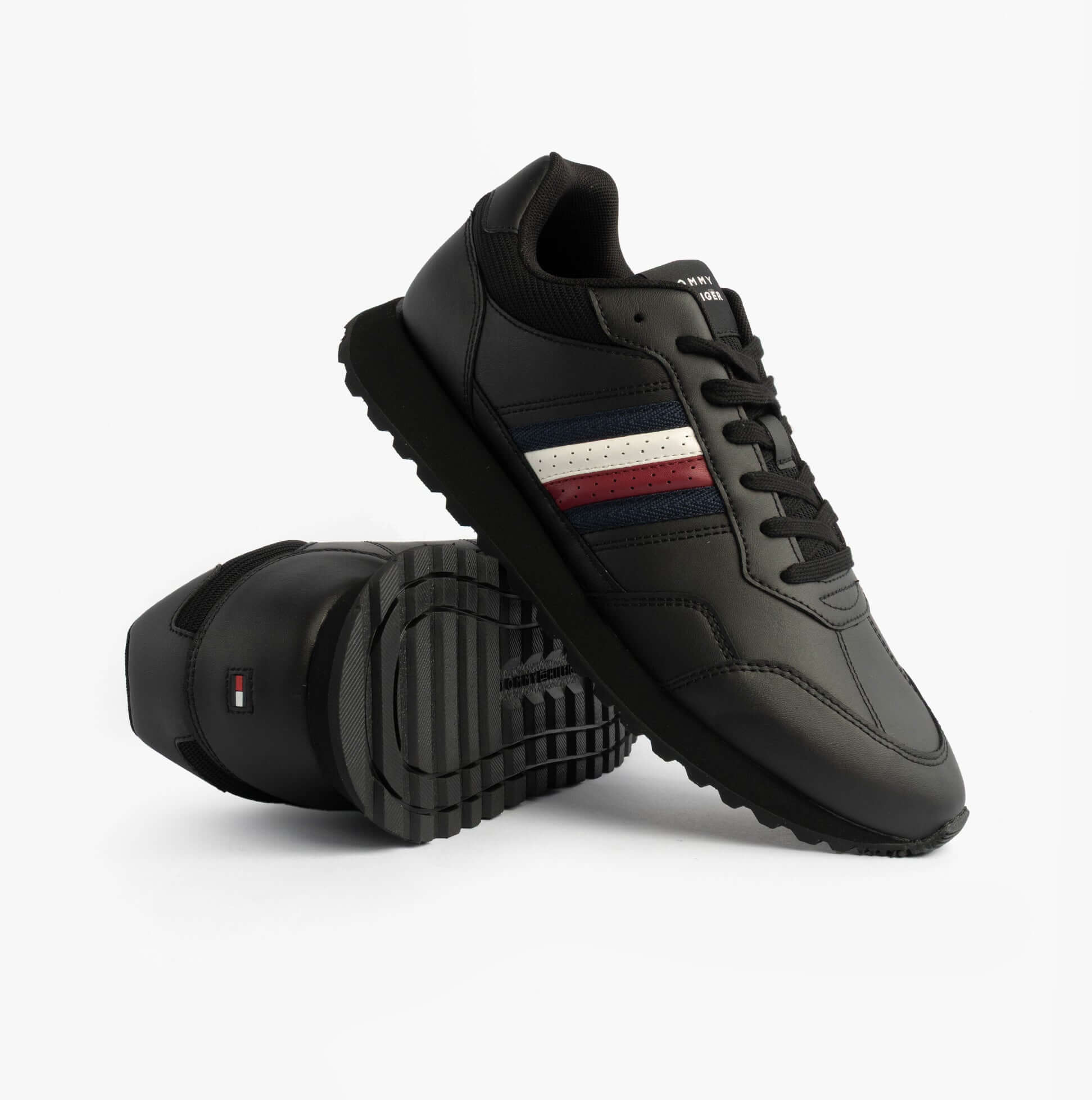 Tommy Hilfiger Mens Signature Tape Cleat Leather Trainers Black side view showcasing the sleek design and striped detailing.