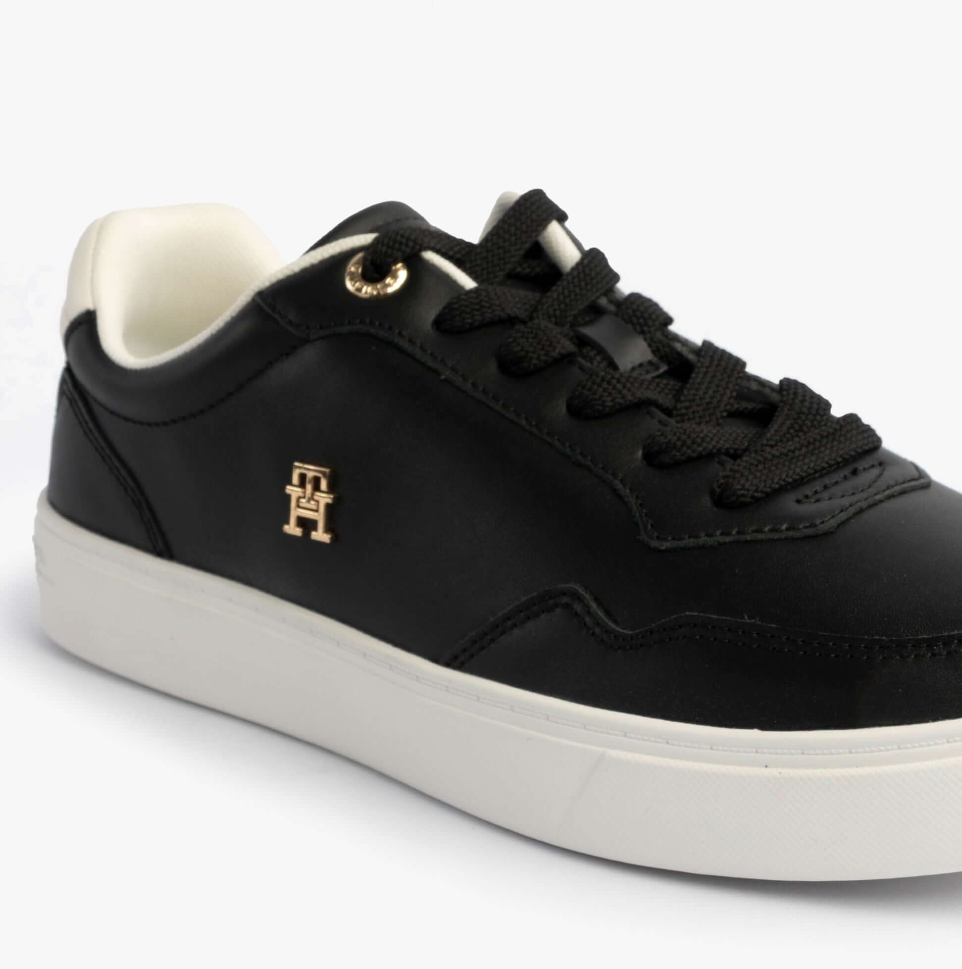 Tommy Hilfiger Womens Leather TH Monogram Plaque Court Trainers Black side view with lace-up closure and gold logo.