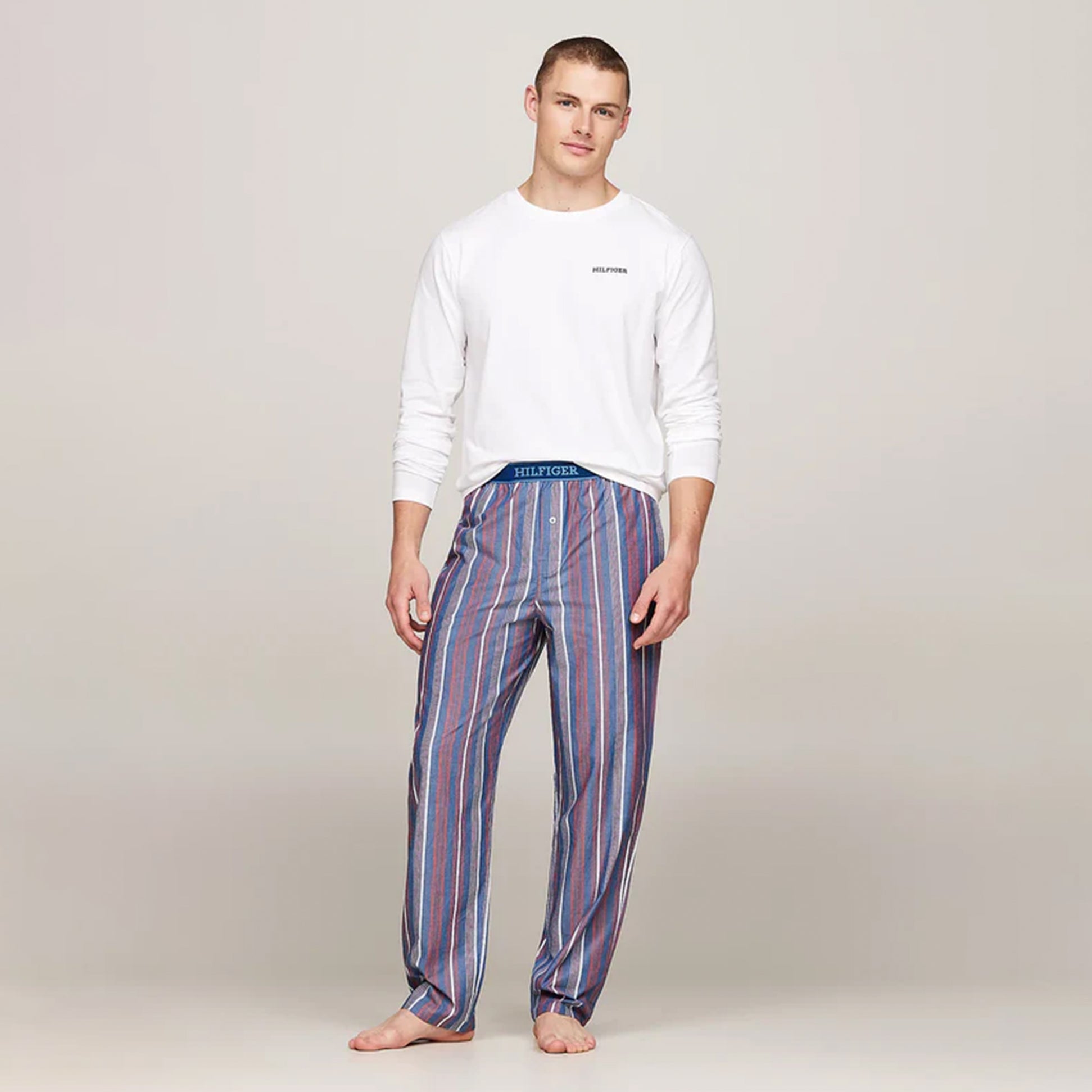 Tommy Hilfiger MONOTYPE Mens Pyjama Set White/Monotype Stripes Indigo front view with model wearing long-sleeve and striped pants.