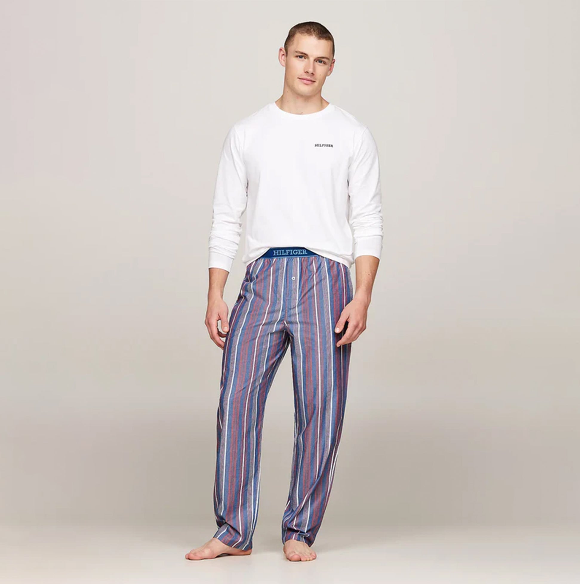 Tommy Hilfiger MONOTYPE Mens Pyjama Set White/Monotype Stripes Indigo front view with model wearing long-sleeve and striped pants.