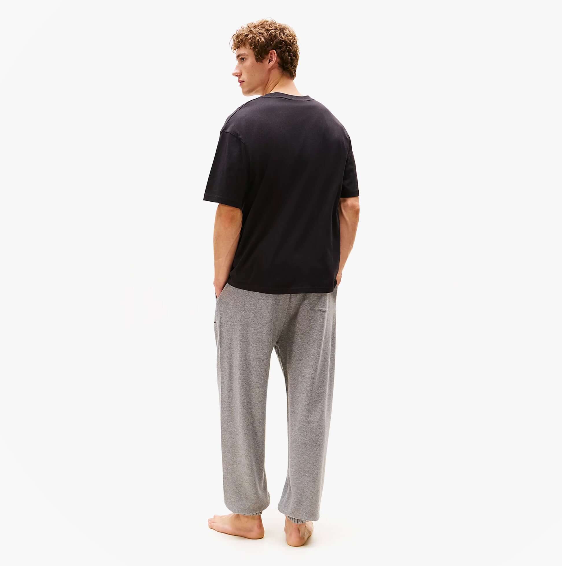 Tommy Hilfiger LOGO T-Shirt Mens Black back view worn with grey pants on model.