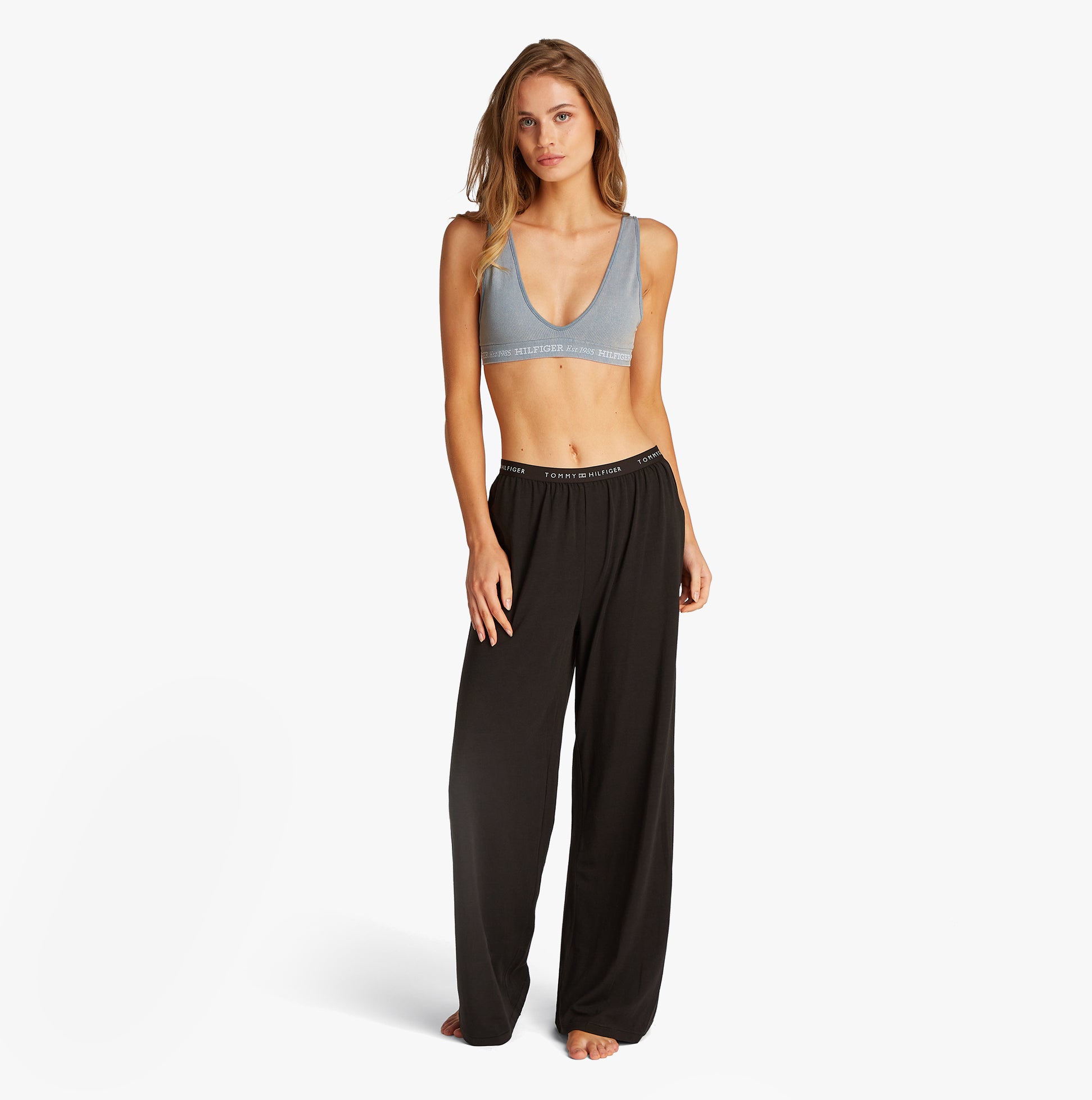 Tommy Hilfiger LOGO Womens Bralette Brisk Blue front view with black pants, showcasing ribbed texture and scoop V-neck design.