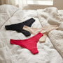 Tommy Hilfiger 3 PACK LACE Womens Thong Multicoloured, side view of black, nude, and red thongs on bed.