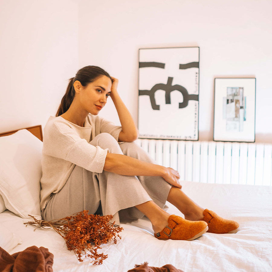 Toni Pons MIMA-FP Womens Slippers Taronja worn by a woman sitting on a bed, side view showcasing the slippers.