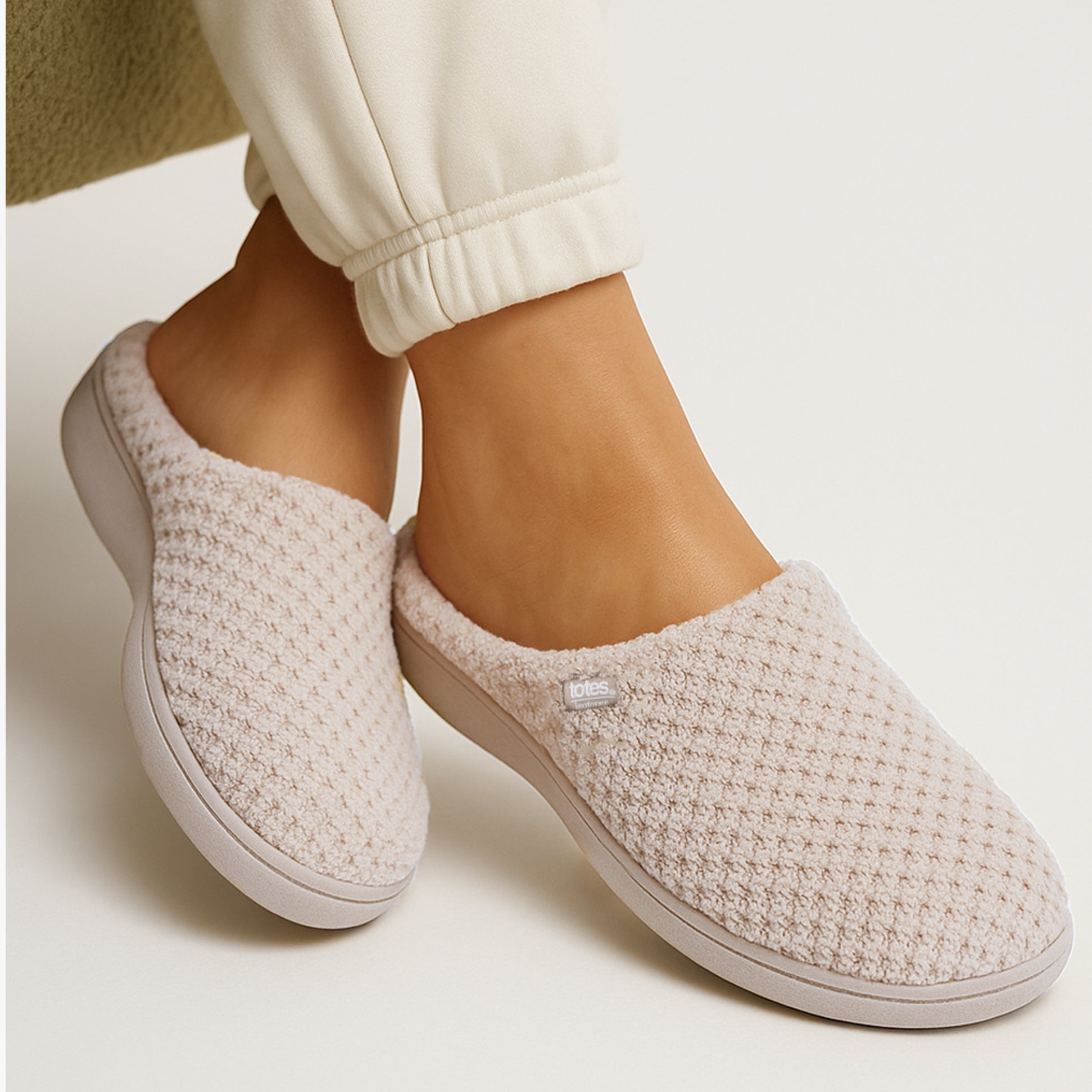 Totes Isotoner POPCORN TERRY Womens Mule Slippers Oat side view with model wearing on foot, showcasing plush texture and comfort.