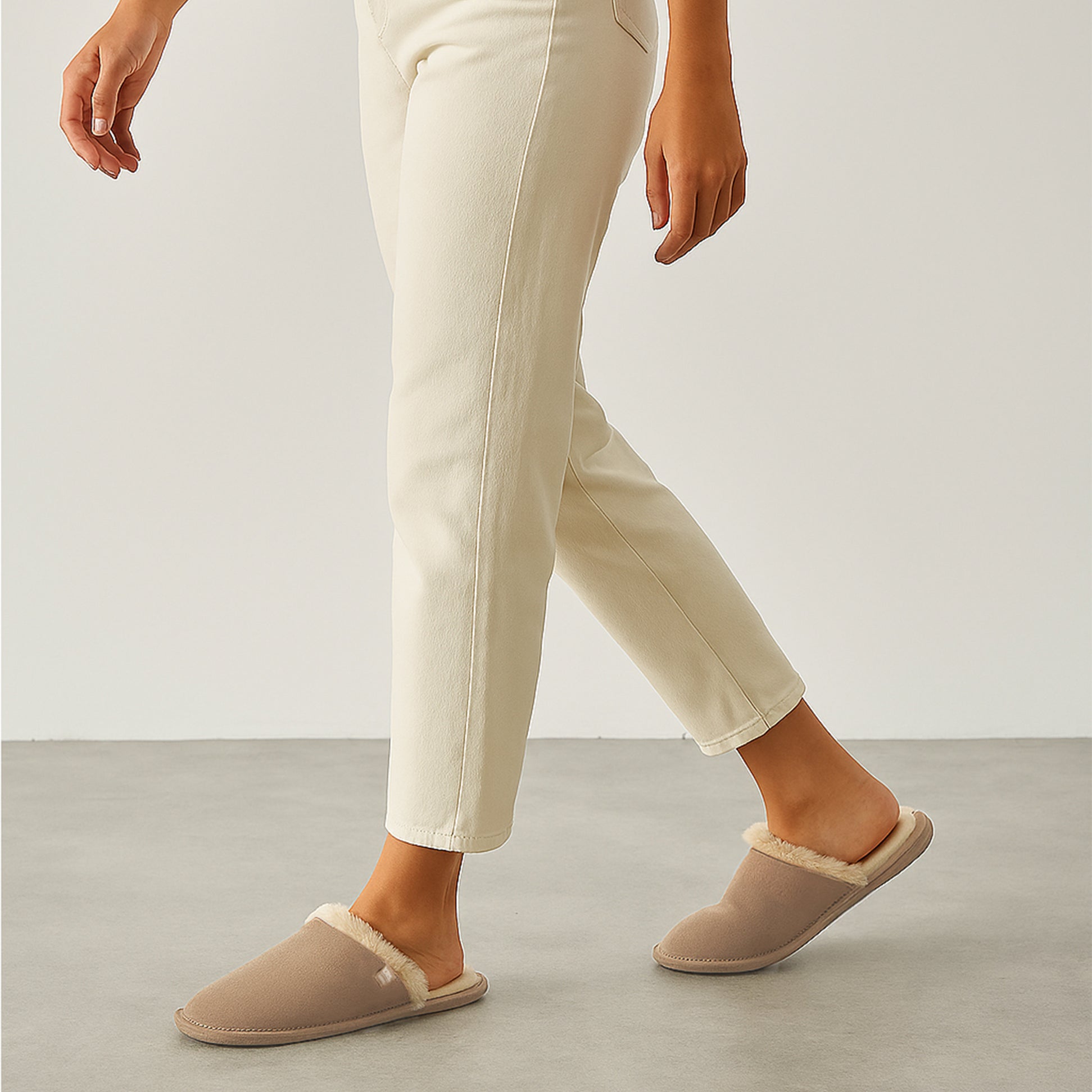 Totes Isotoner REAL SUEDE MULE Womens Slippers Sand side view worn by model with cream pants.