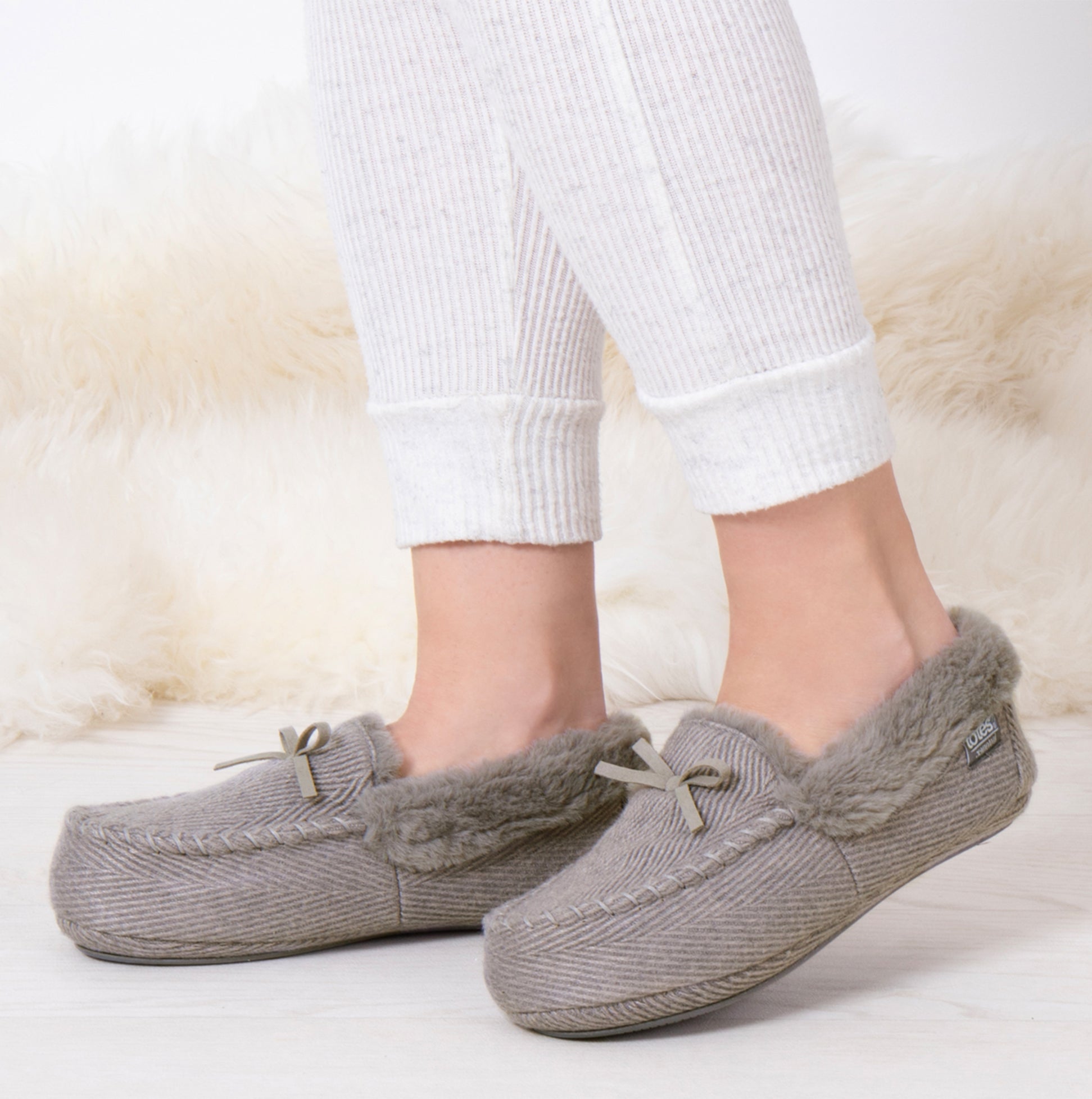 Totes Isotoner HERRINGBONE MOCCASIN WITH FUR CUFF Womens Slippers Grey side view on model's feet with white leggings