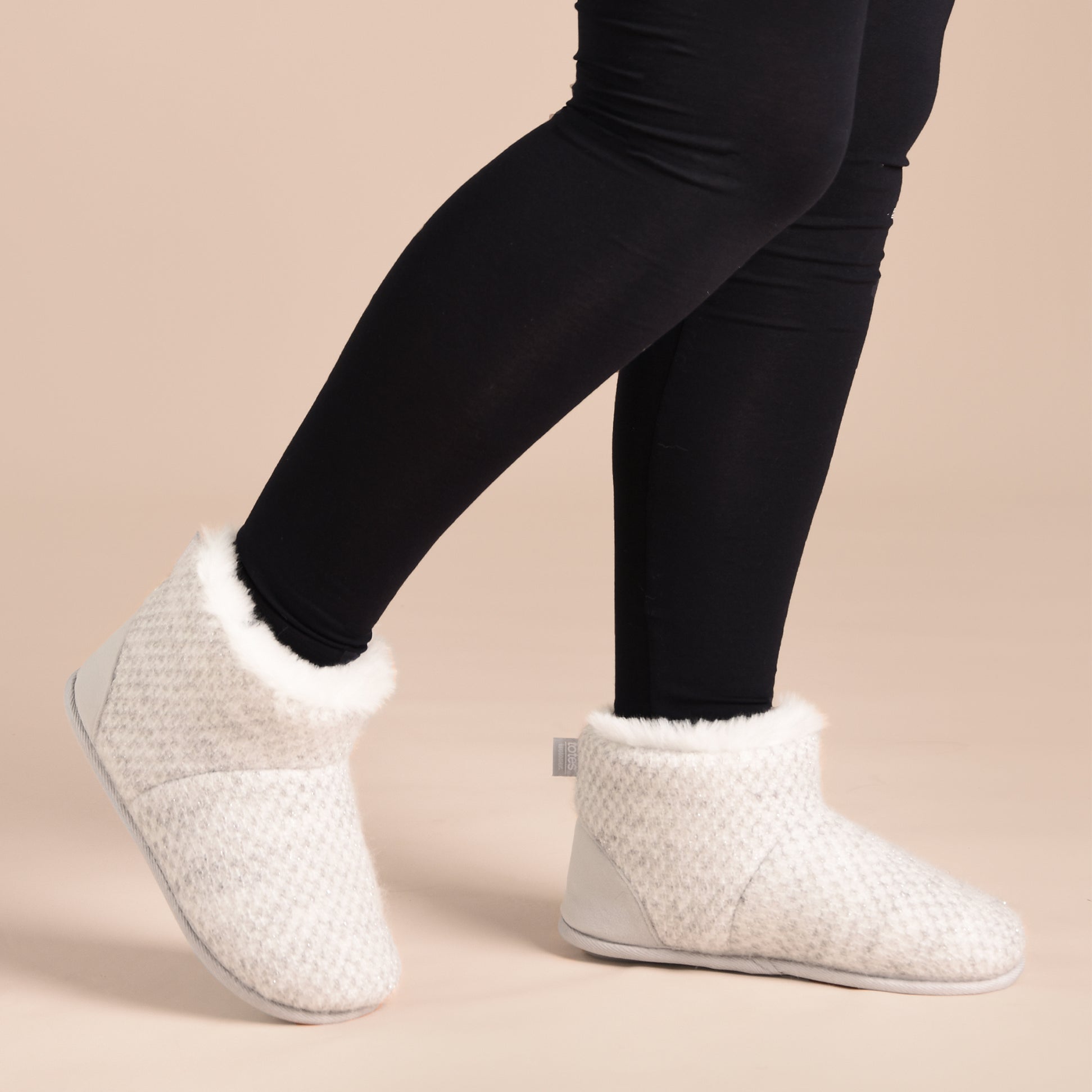 Totes Isotoner SPARKLE KNIT Womens Boot Slippers Light Grey side view worn by model with black leggings.
