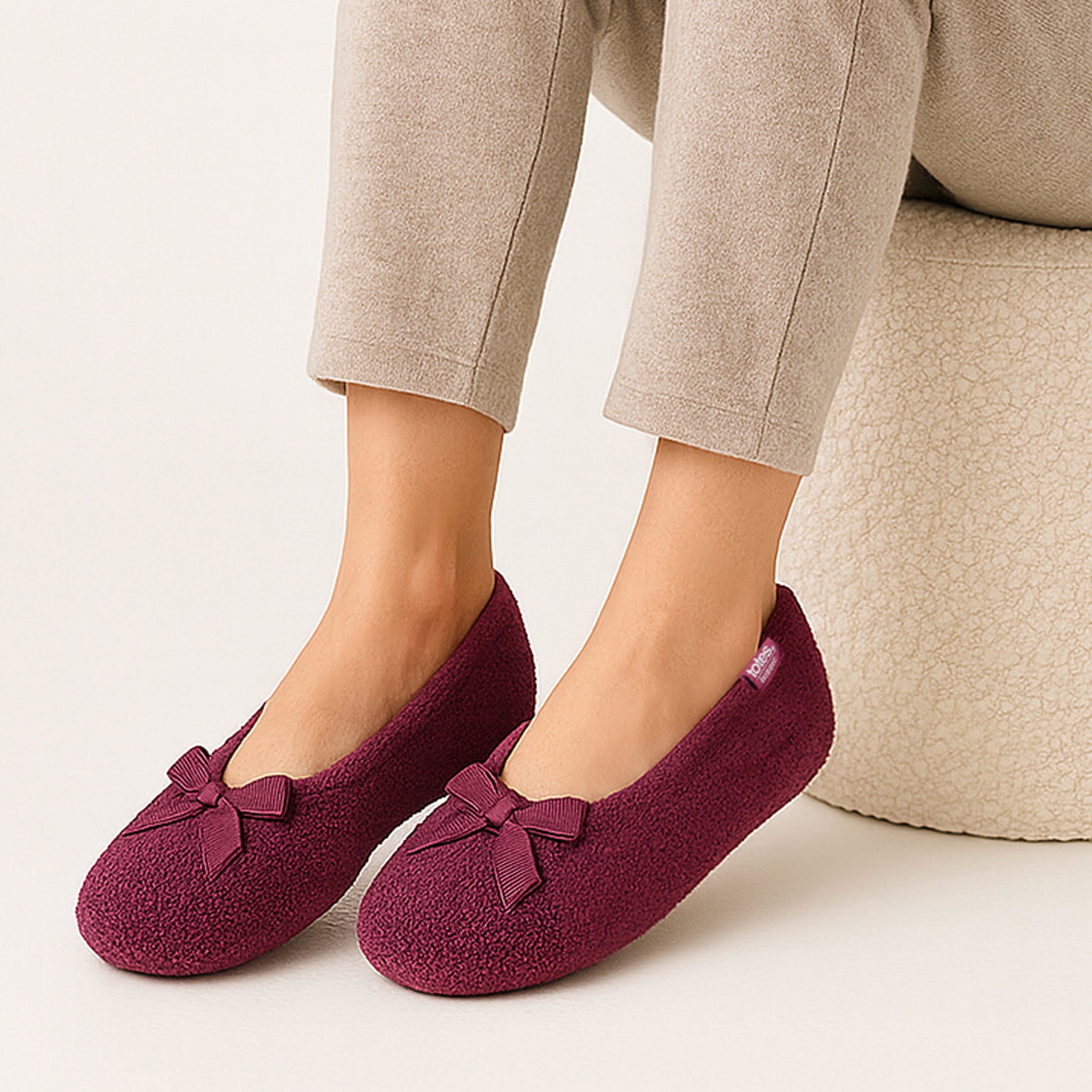 Totes Isotoner STRETCH TERRY BOW Womens Ballerina Slippers Burgundy side view on a model's feet.