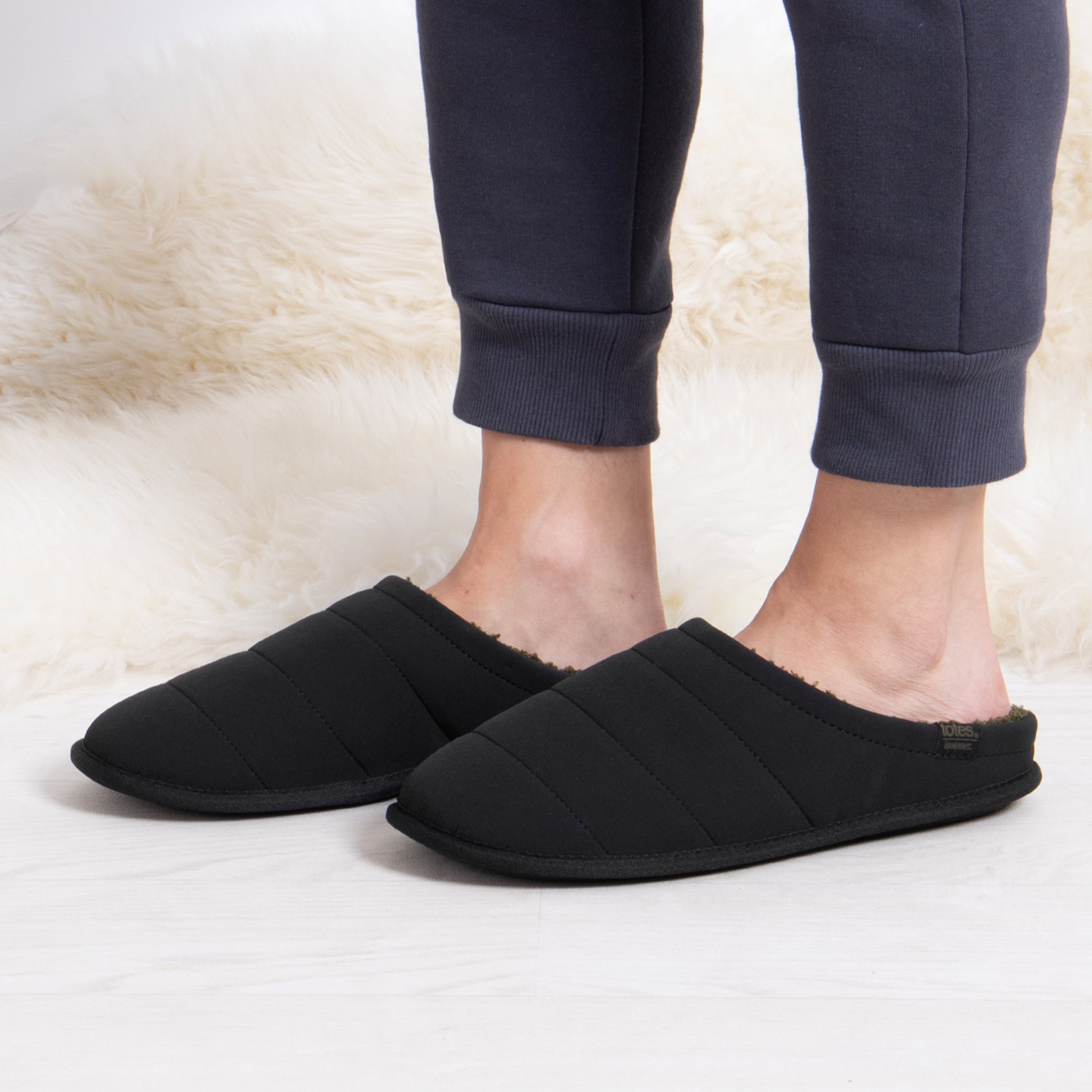 Totes Isotoner SPORT QUILTED MULE WITH COSY LINING Mens Mule Slippers Black side view worn with joggers.